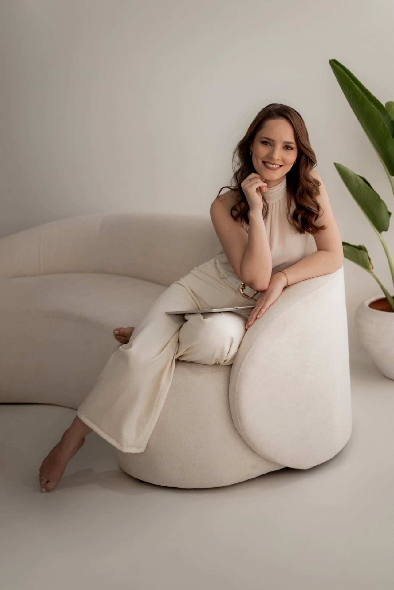 Bruna Hoschler sorrindo, sentada em um poltrona clara